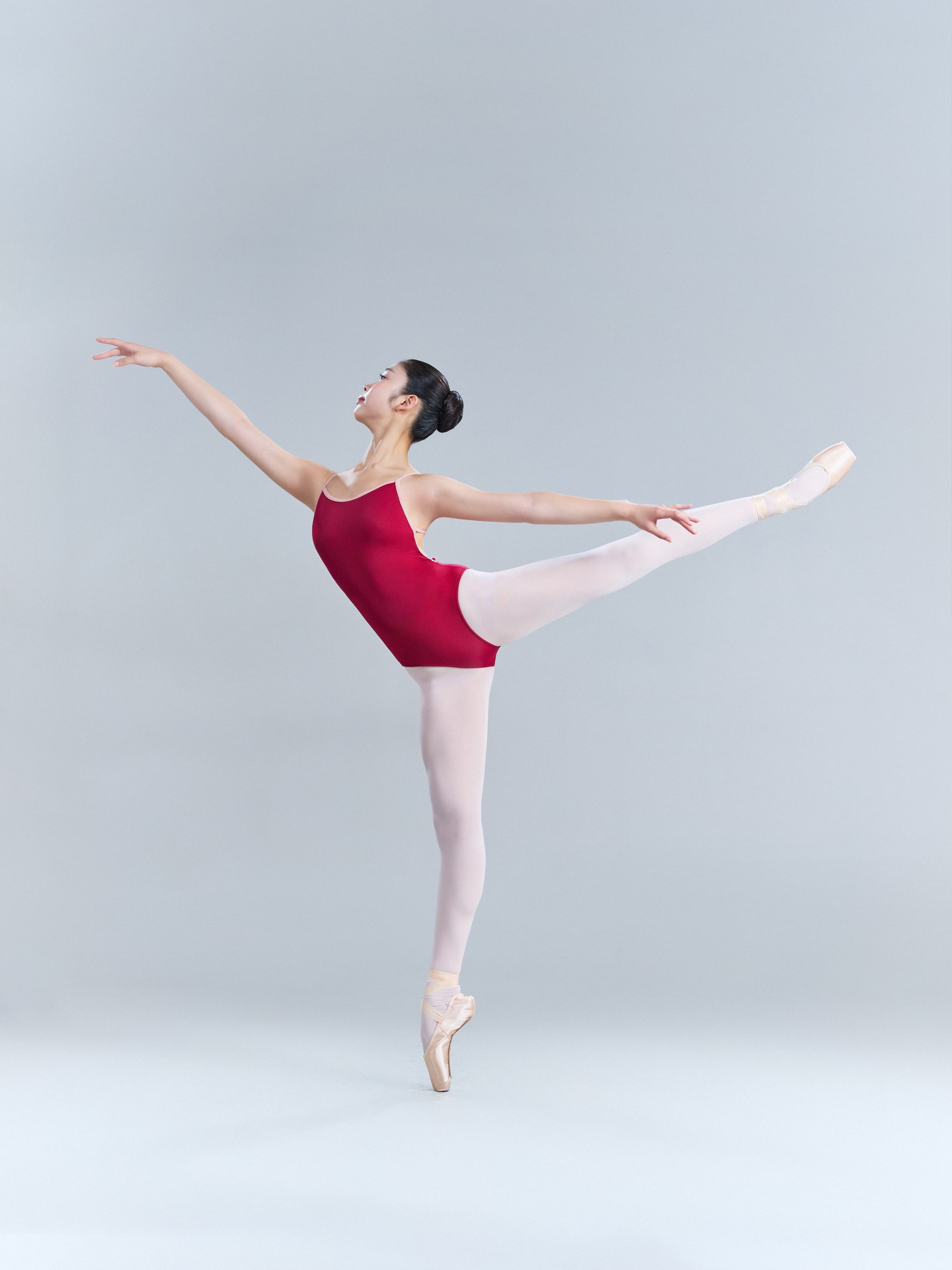 Arabesque en pointe in a red leotard, arms open