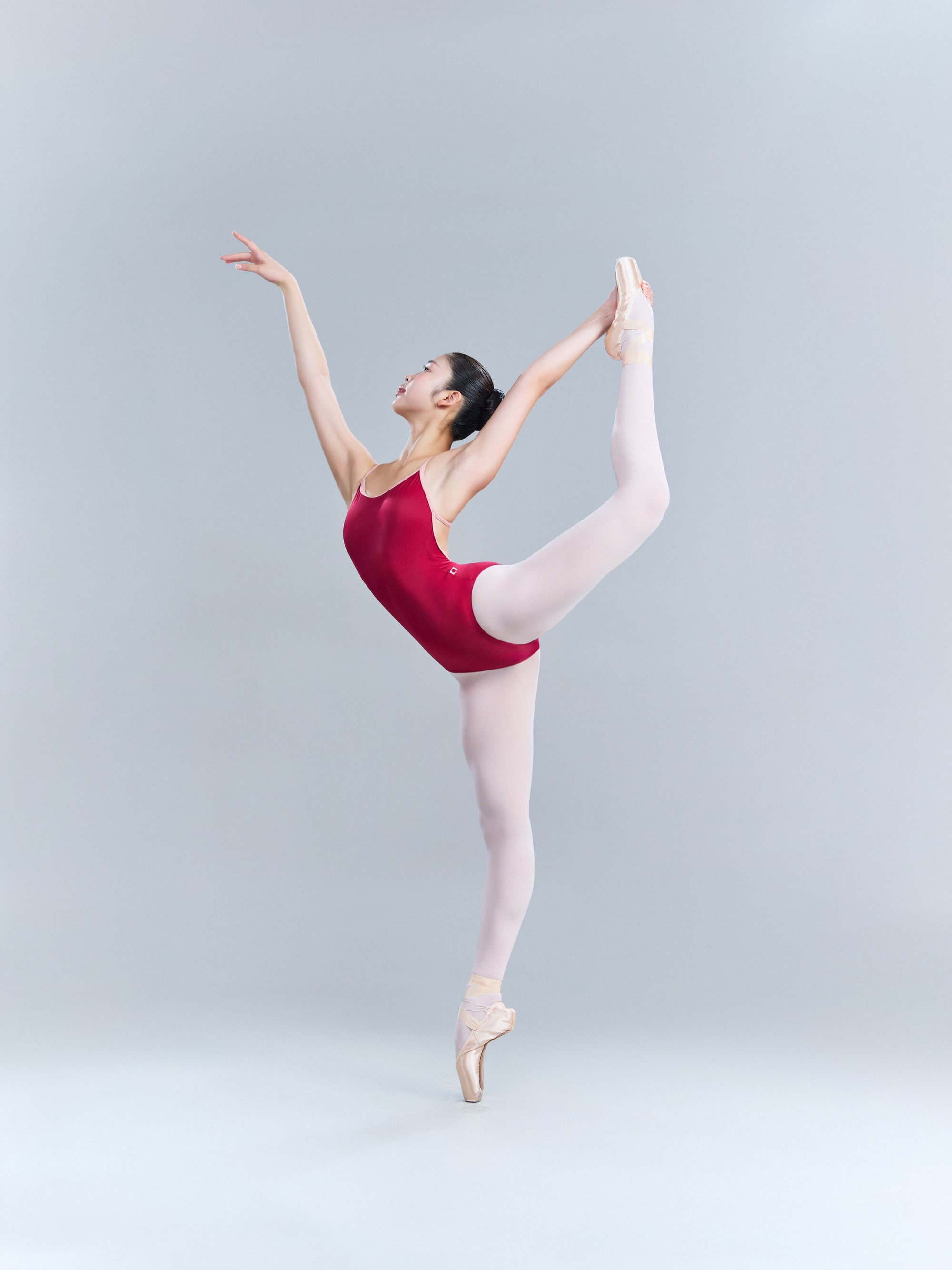 Développé à la seconde en pointe in a red leotard
