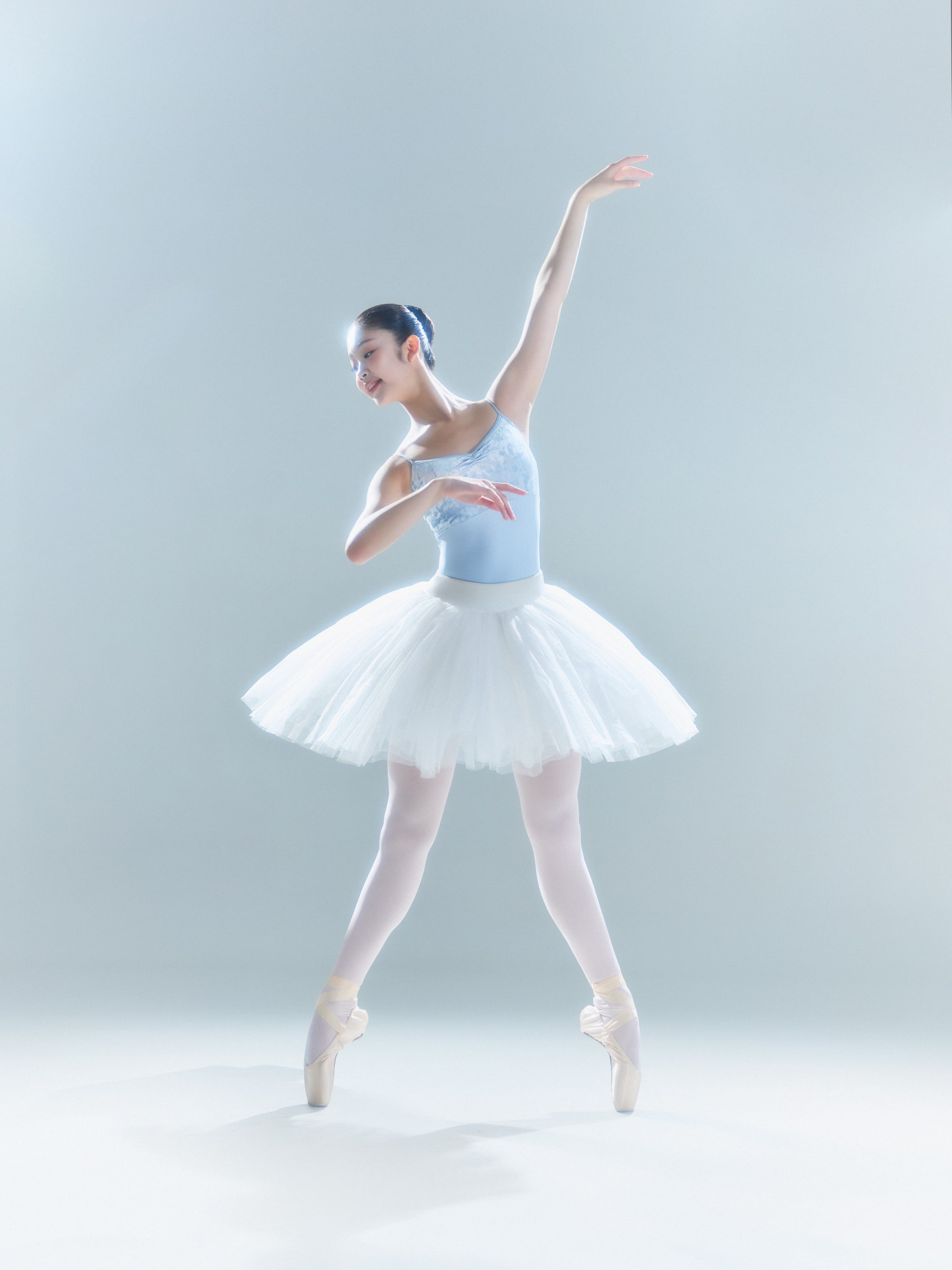 En pointe in a white classical tutu, arms in third