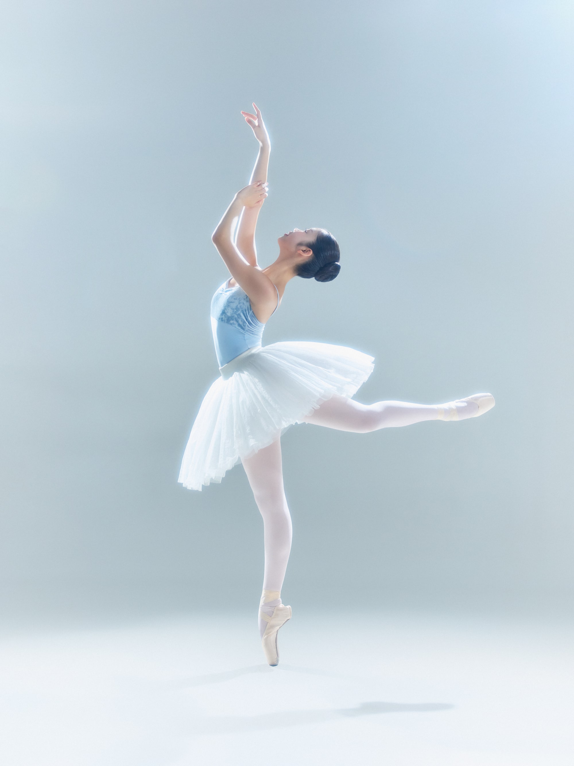 Arabesque in a white classical tutu, arms lifted