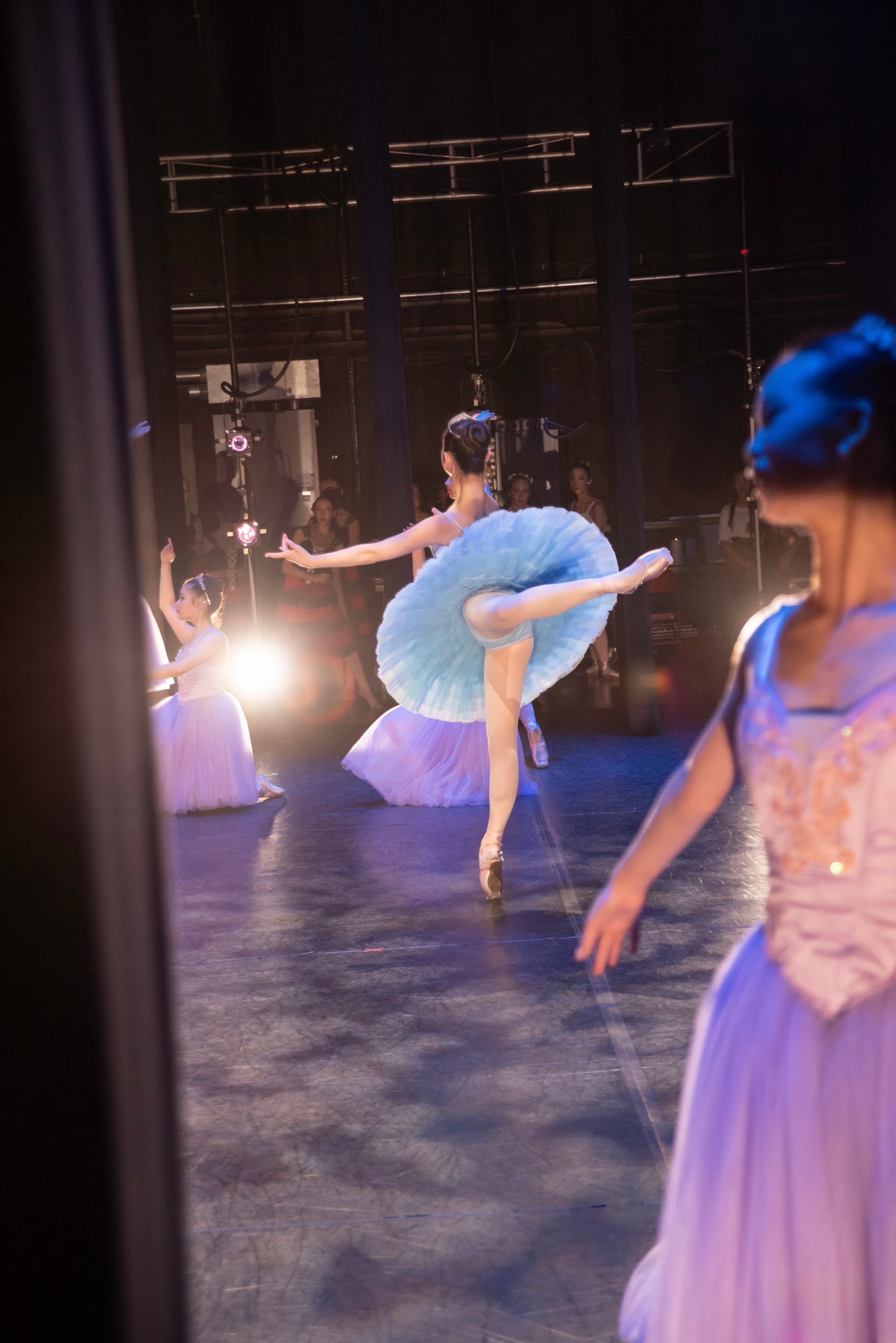 Arabesque in a blue classical tutu, seen from the wings